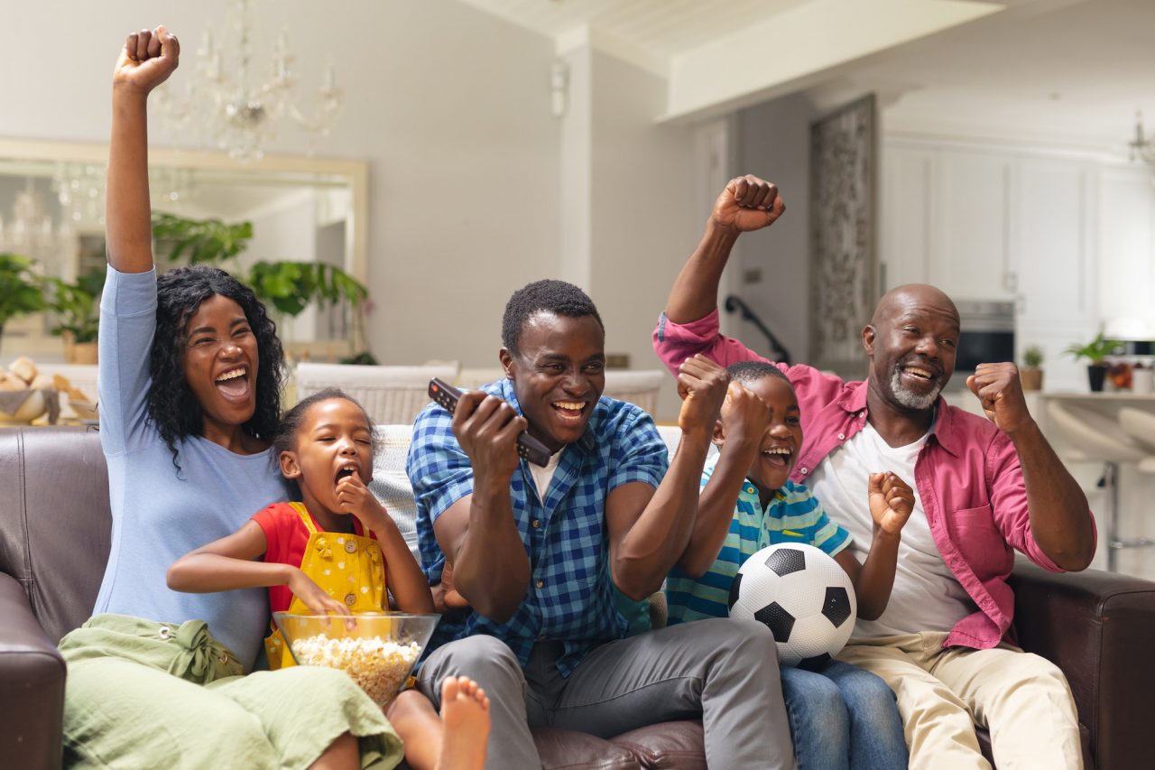 A family cheering together in front of the television during a HawkTV broadcast