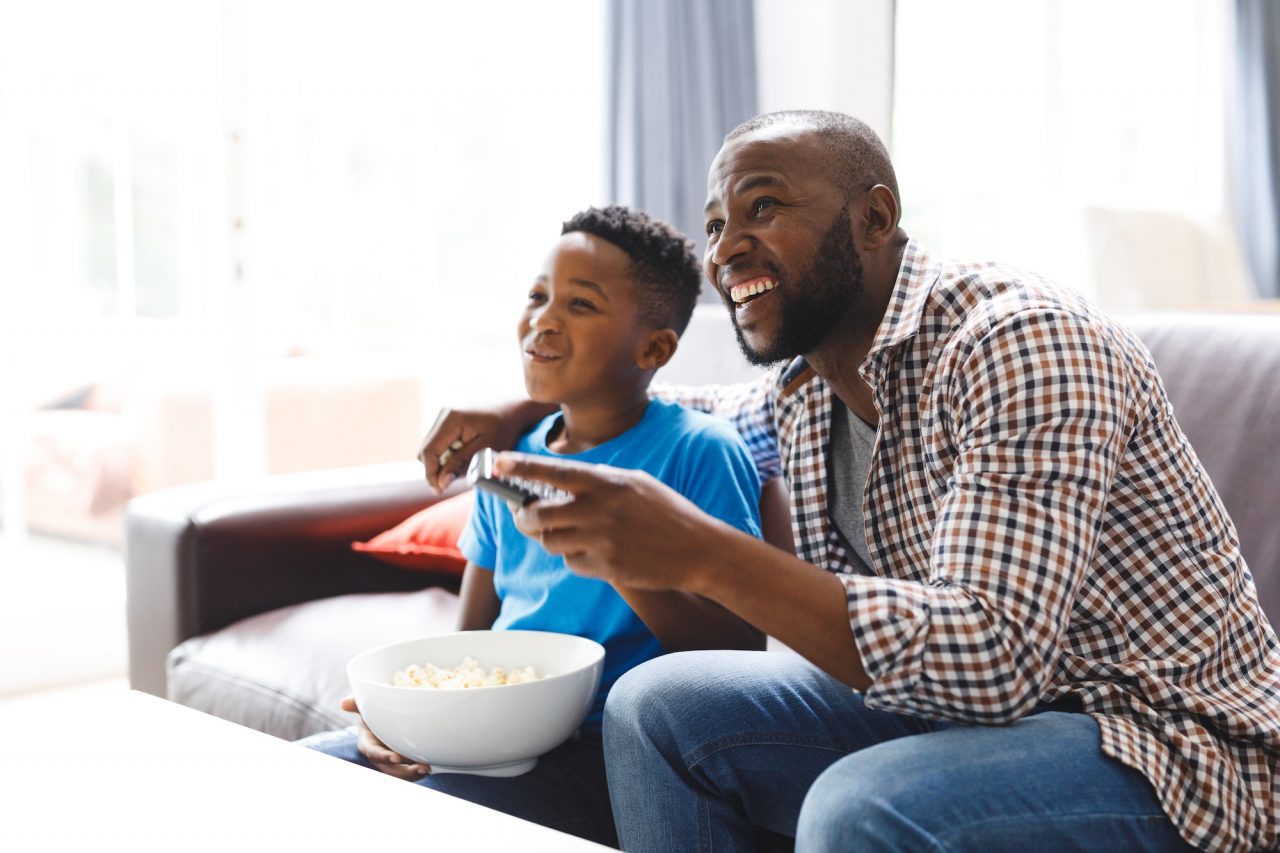 A father and son watching a HawkTV kids channel together on the sofa